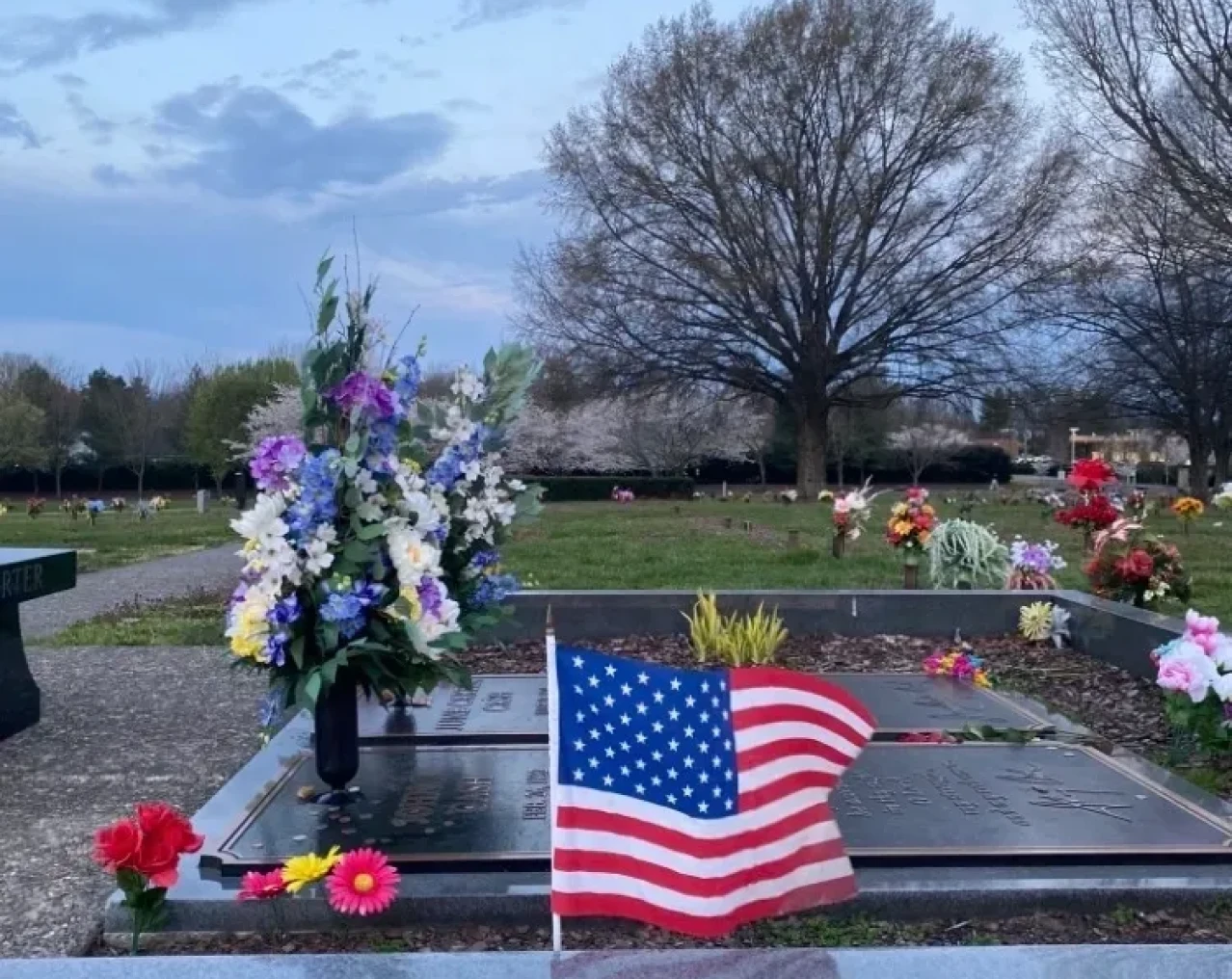 Cemetery tombstone adorned with colorful flowers